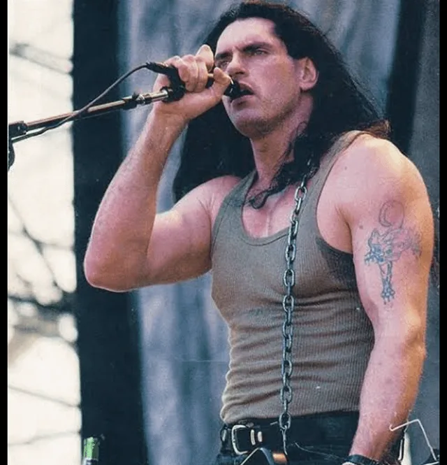 Peter Steele singing into a microphone on stage, wearing a tank top and chain
